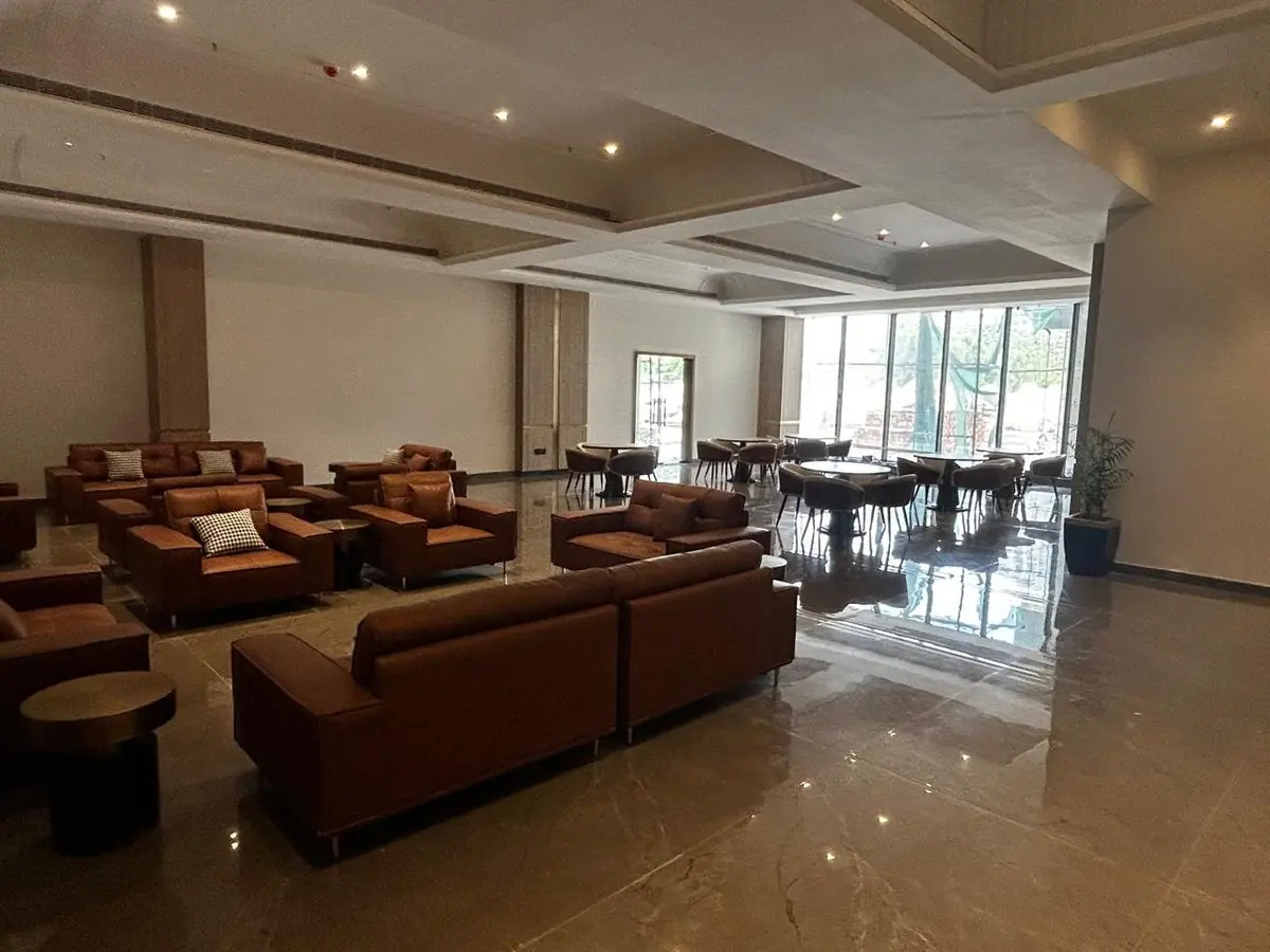 The finished clubhouse lounge at AIGIN Royal Park photographed on site, furnished with sofas and armchairs in front of full-height glazing