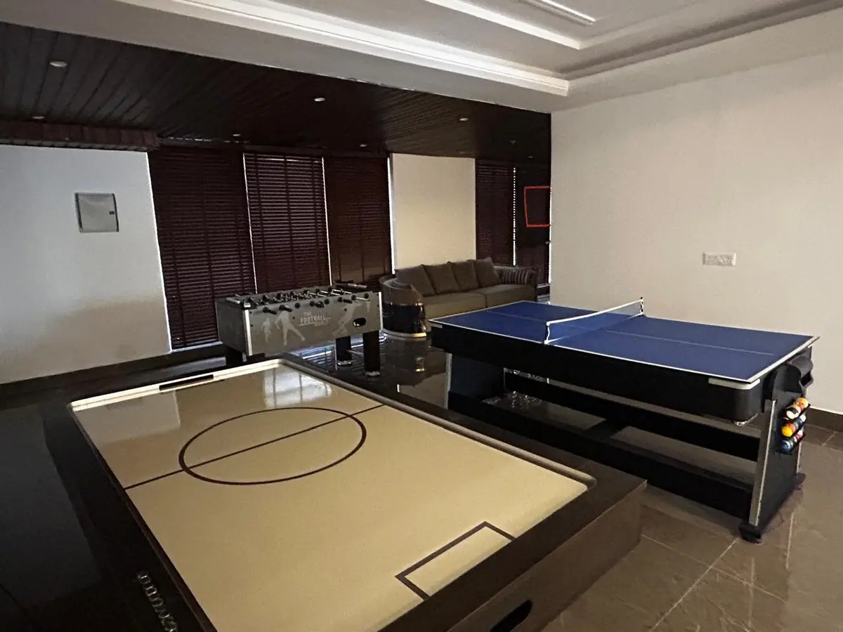 Indoor games area at the AIGIN Royal Park clubhouse with an air hockey table and a table-tennis table, photographed on site