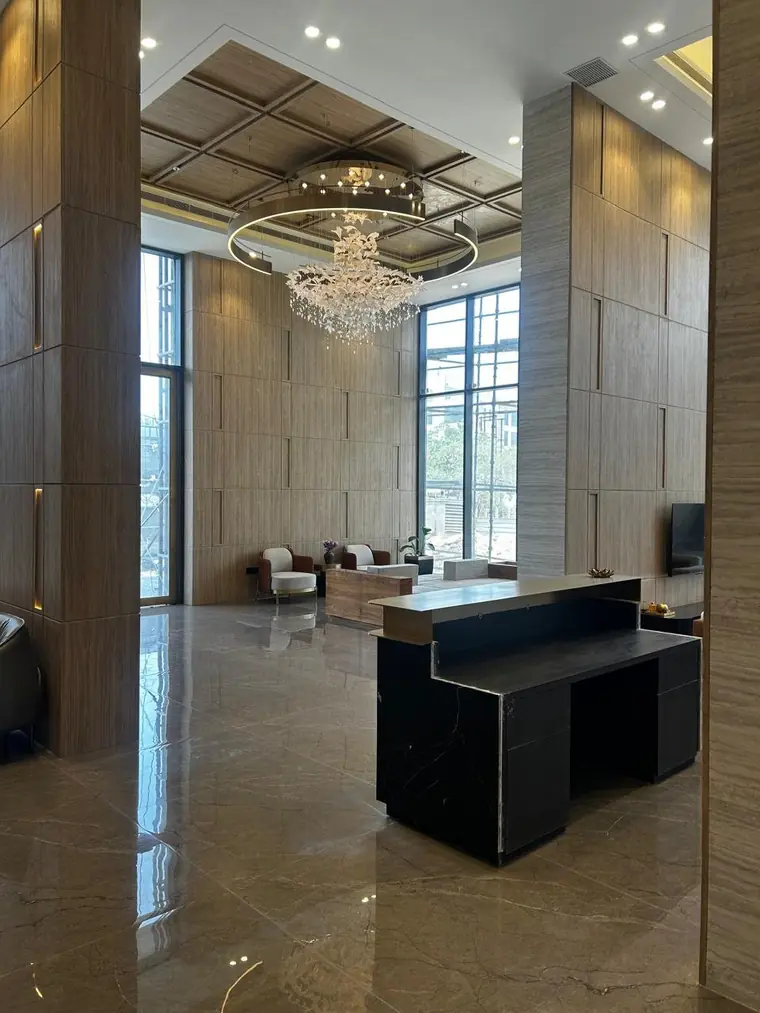 Lounge off the entrance lobby at AIGIN Royal Park with stone-clad columns and full-height glazing onto the grounds, photographed on site