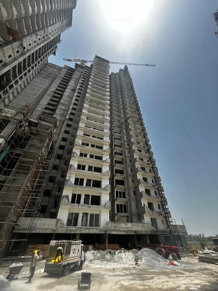Tower crane working the upper floors of an AIGIN Royal Park tower on NH-24 Ghaziabad, with the exposed slab edges of the topmost levels still to be clad