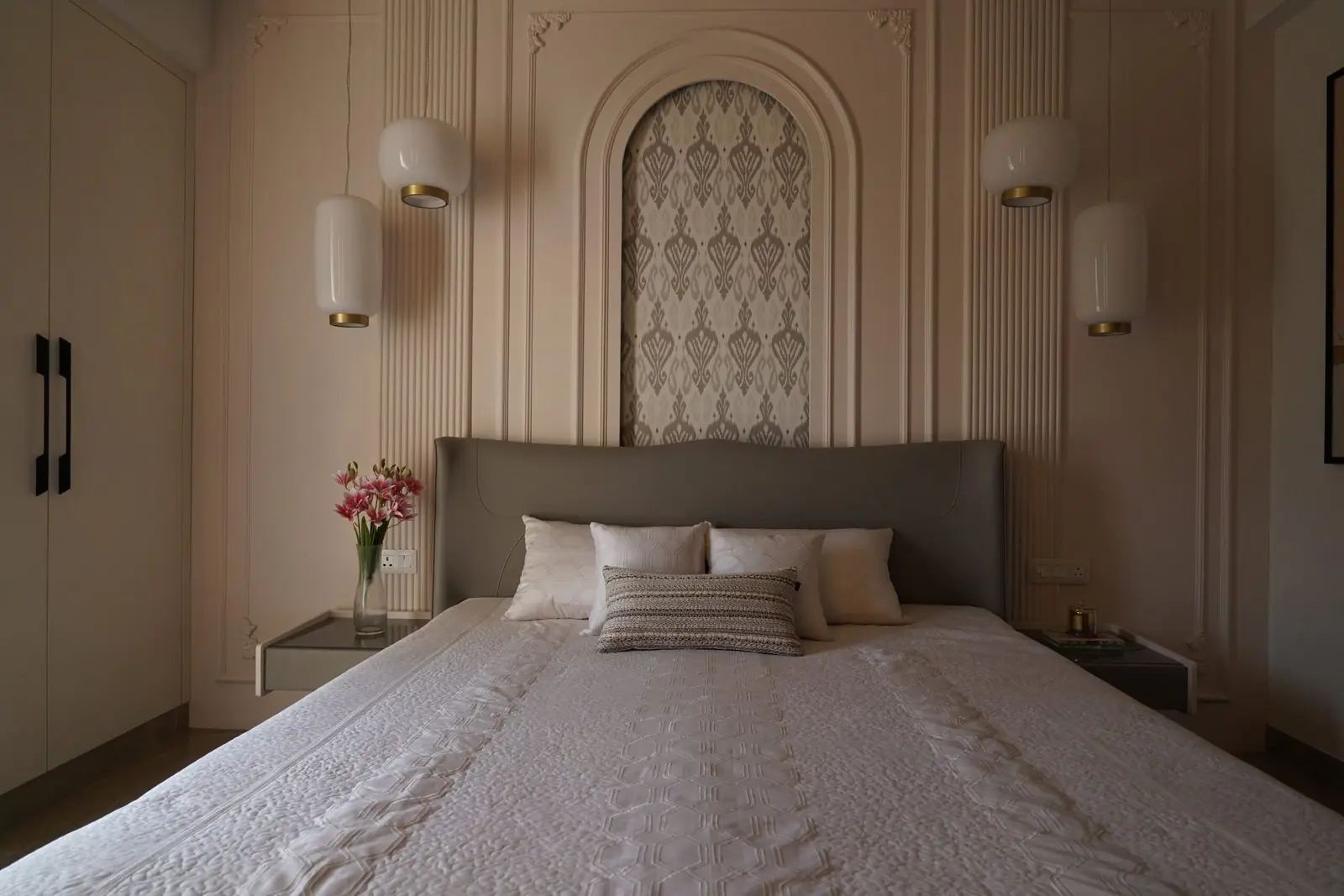 Master bedroom with an arched patterned headboard panel and matching wall lights in the sample apartment at AIGIN Royal Park, Ghaziabad
