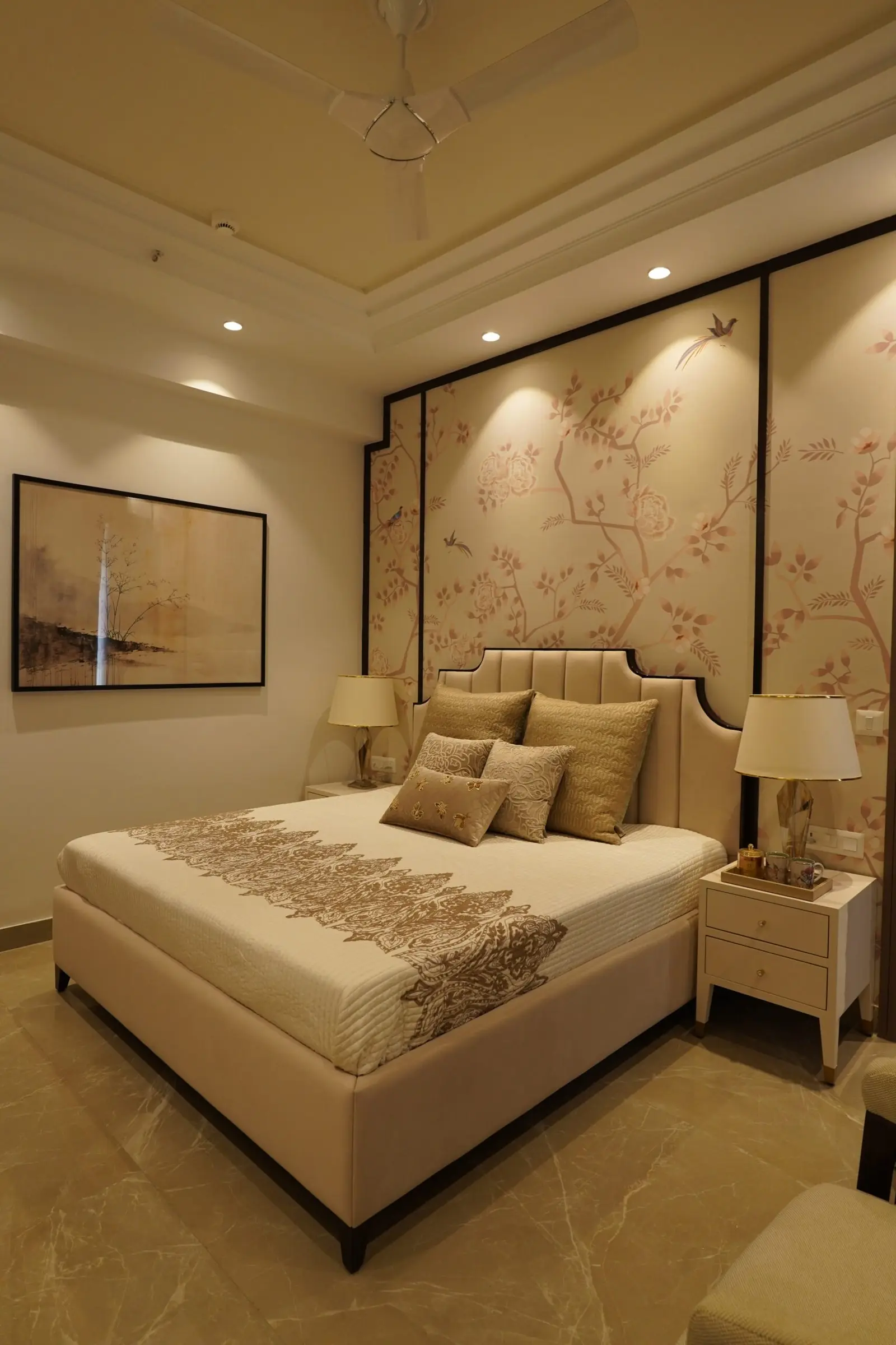 Bedroom with floral wallpaper, an upholstered headboard and bedside lamps in the sample apartment at AIGIN Royal Park, Ghaziabad