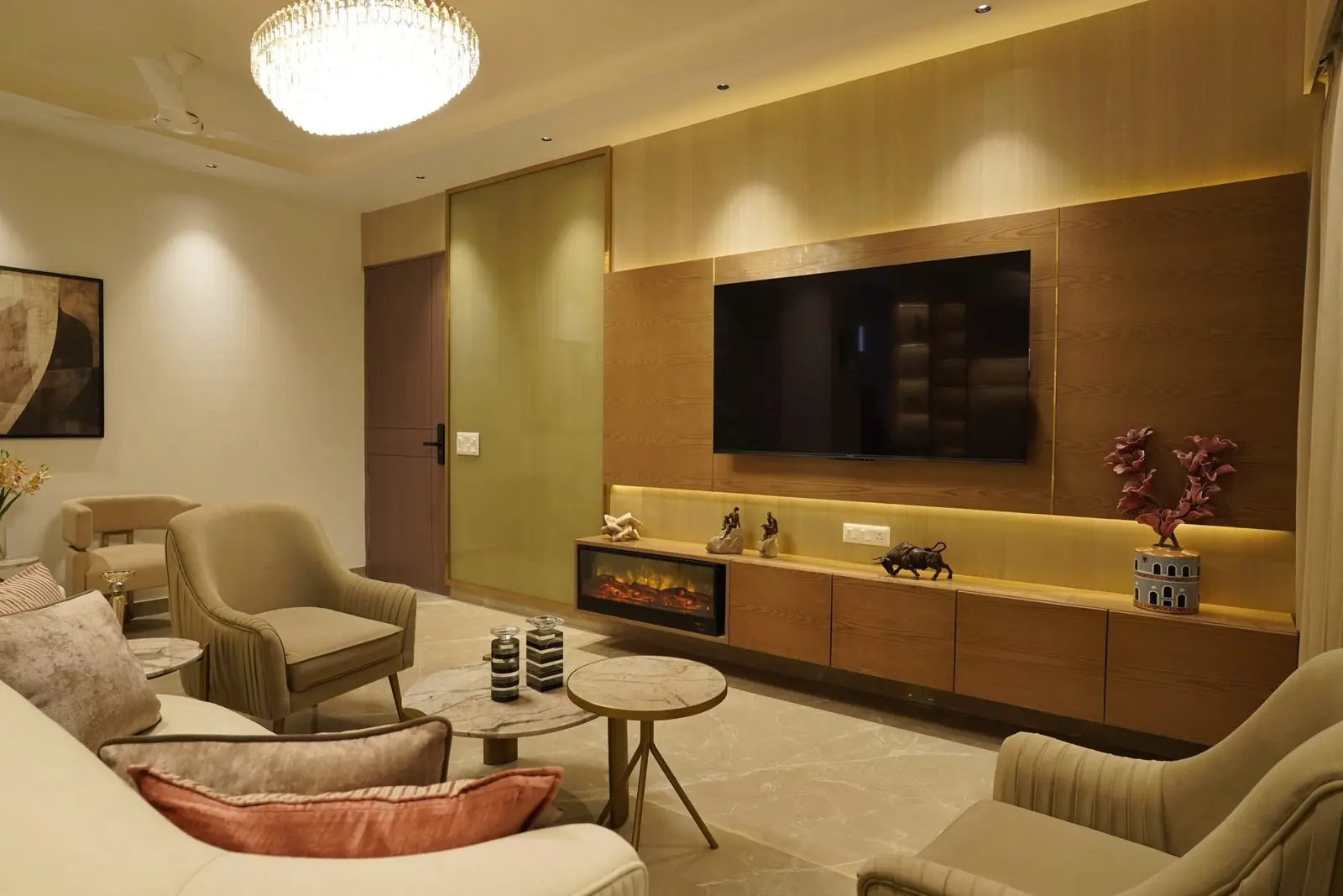 Living room with a media wall, chandelier and armchairs in the finished sample apartment at AIGIN Royal Park, Ghaziabad