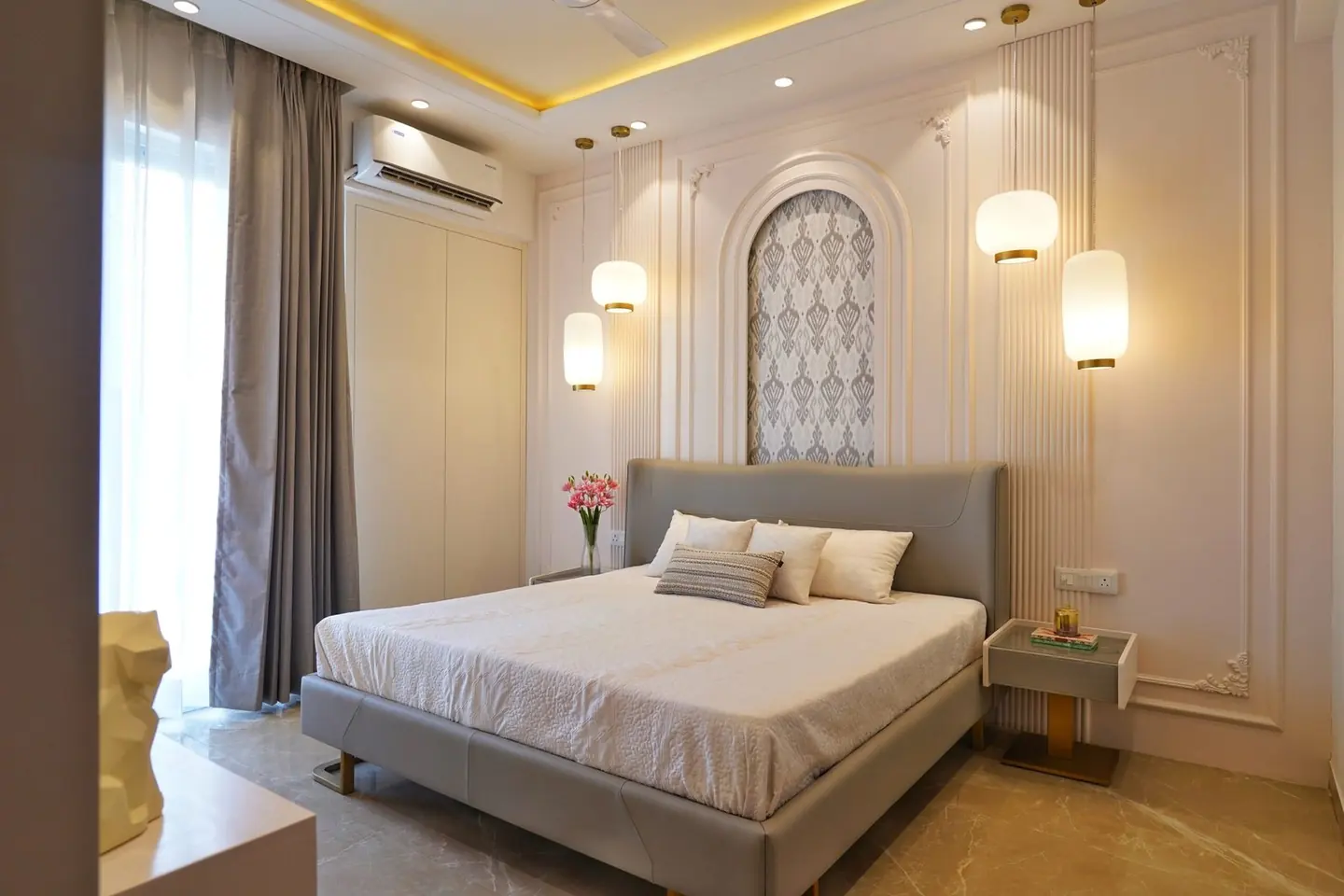Photograph of a bedroom in the AIGIN Royal Park sample apartment, Ghaziabad, finished with pendant lighting and a fitted wardrobe
